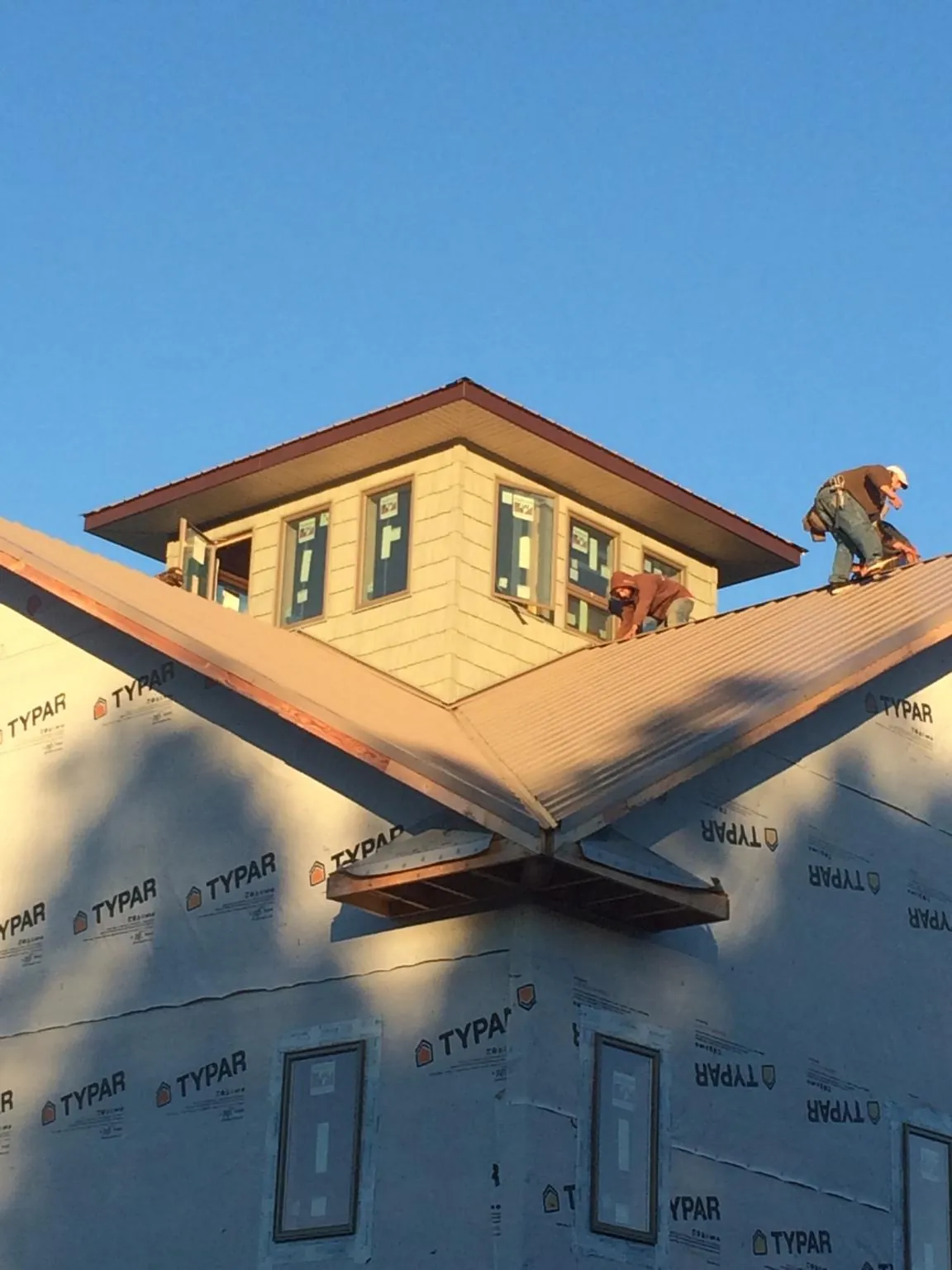 Roofers working around a rooftop cupola on a new metal roof at sunset — Roof Waterproofing in Adamsville by Roofing Brothers